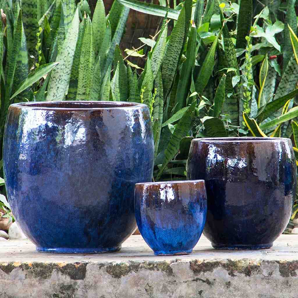Dark blue round ceramic bulbous planters featuring smooth curves and contrasting brown rim accents