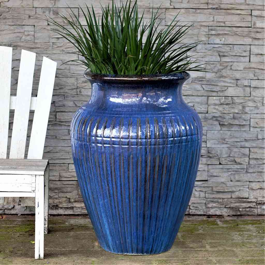 Fluted amphora planter in blue with black accents, featuring a textured, vertical ribbed design