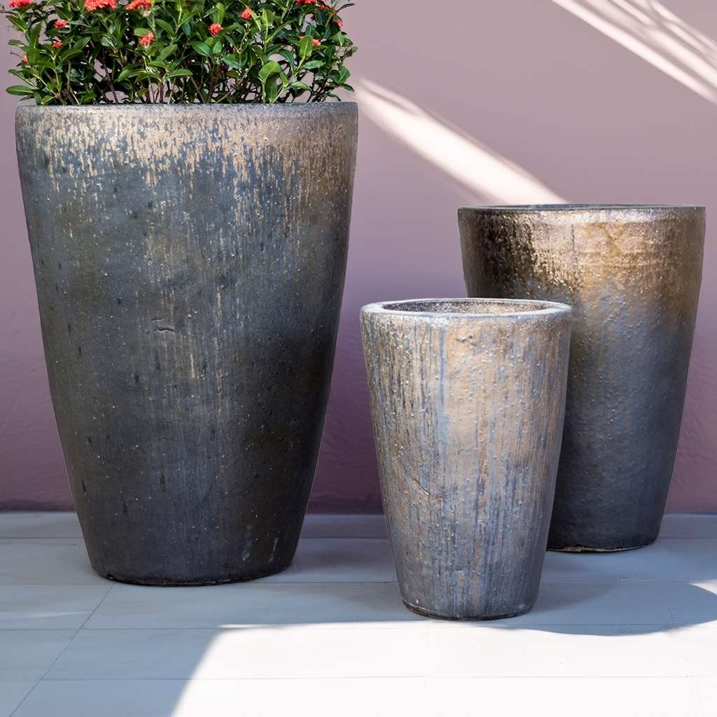 Tall cylinder planters in a weathered grey finish with metallic accents, offering a rustic and contemporary look