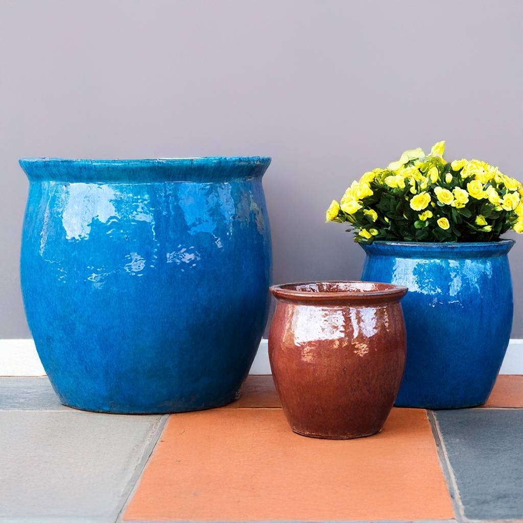 Three rounded ceramic planters featuring a glossy finish—two in vibrant blue and one in rich brown
