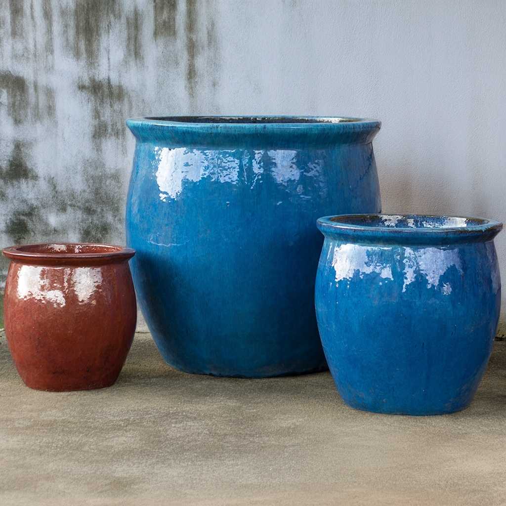 Three rounded ceramic planters featuring a glossy finish—two in vibrant blue and one in rich brown