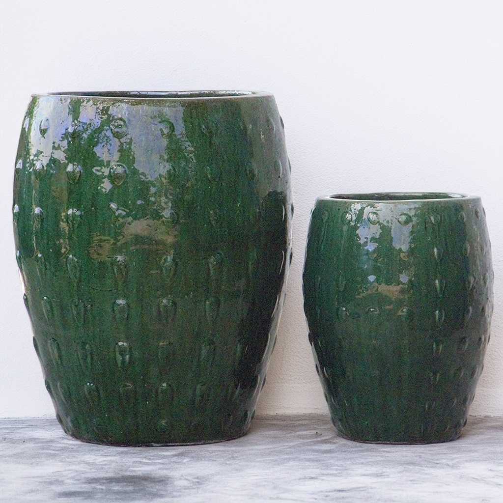Barrel-shaped planters in glazed dark green featuring a raised dot texture