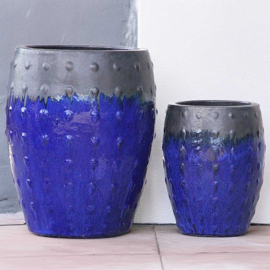 Barrel-shaped planters in dark blue featuring a gray dripping effect and raised dot texture