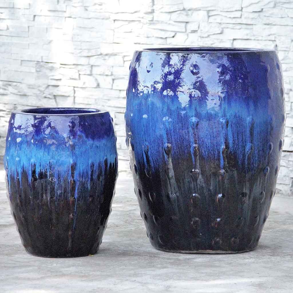 Barrel-shaped planters in blue, light blue, and black featuring a raised dot texture