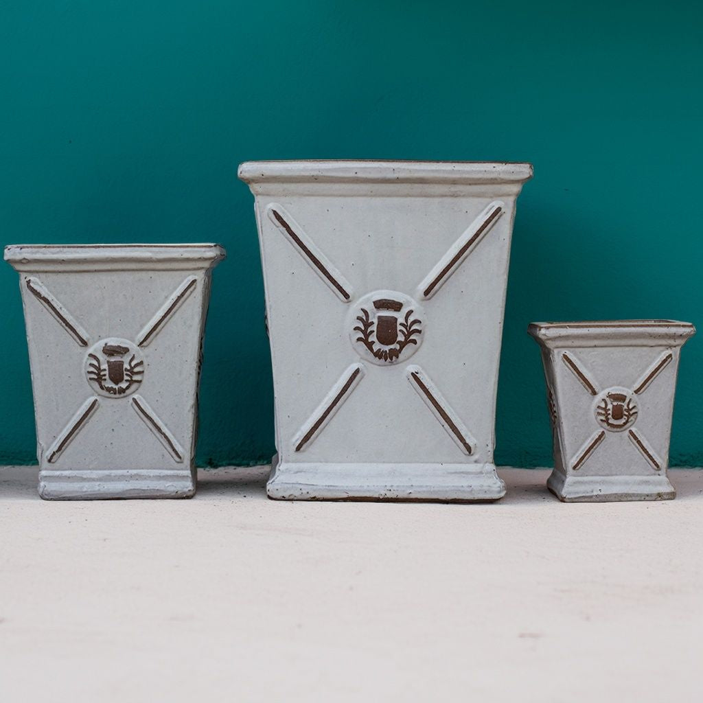Square ceramic planters in rustic white with flared rims and embossed regal motifs