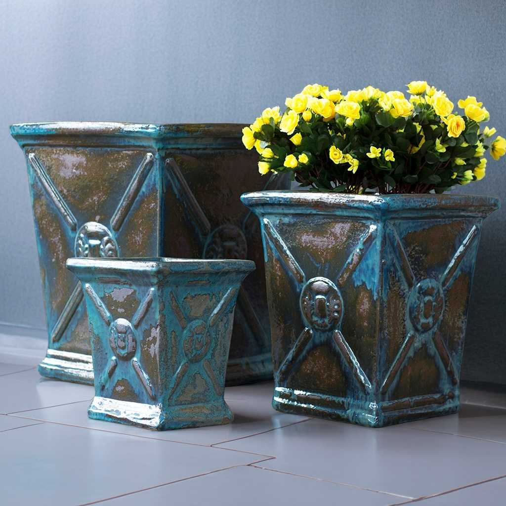 Glossy square ceramic planters in turquoise with brown accents, featuring a flared rim and embossed regal motif for an elegant, decorative touch