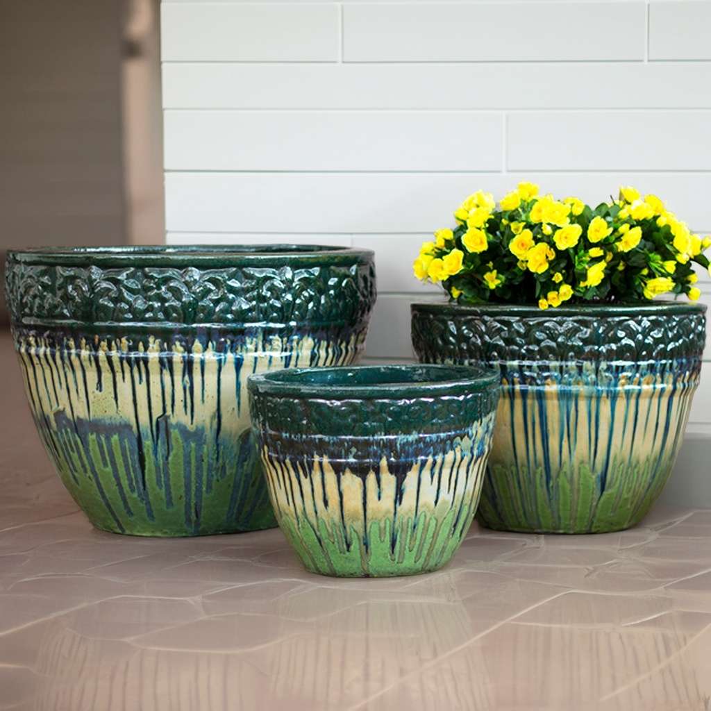 Round ceramic planters in forest green featuring an ombre base fading from green to light yellow, adorned with blue marbling and embossed floral rims