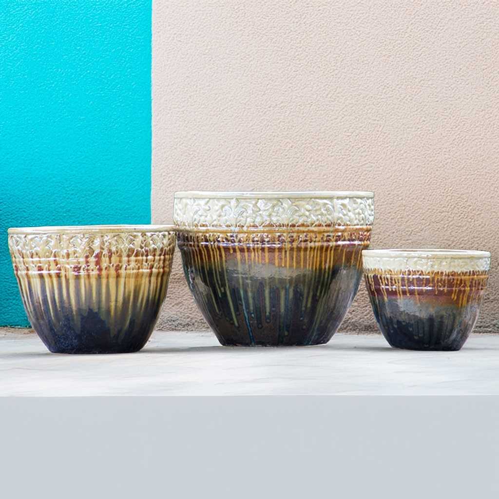Round ceramic planters with a drip-glazed effect in cream, brown, and dark blue, featuring embossed floral rims