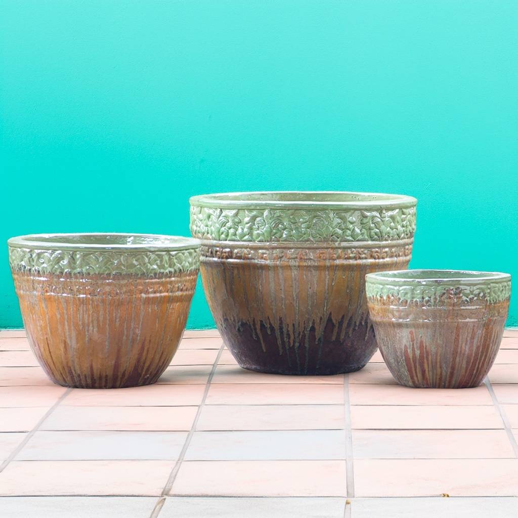 Round ceramic planters featuring a drip-glazed effect in light green, orange, and brown, accented with embossed floral rims