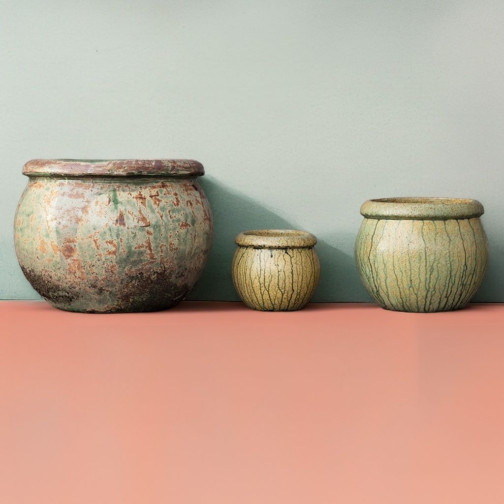 Round ceramic planters with a weathered, mottled finish in faded green, brown, and gray tones