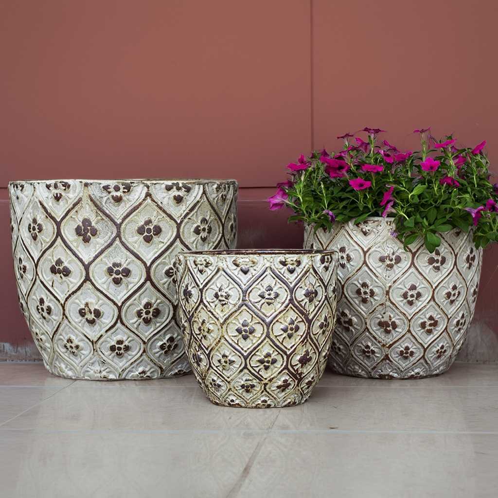 Ivory round planters with a distressed, antiqued finish and raised floral lattice texture