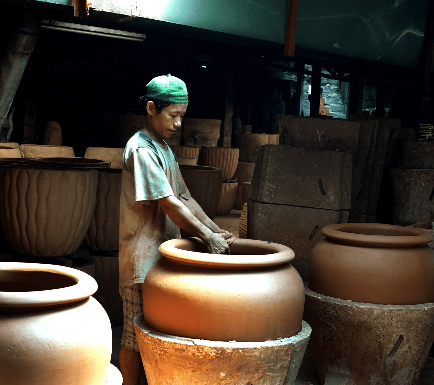 Vietnamese artisan carefully handcrafting a large clay pot using traditional techniques