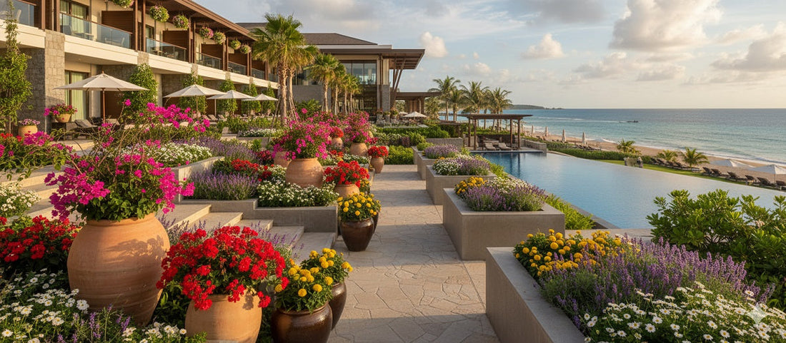 A luxury resort with vibrant flower gardens, an infinity pool, and the ocean in the background under a partly cloudy sky.