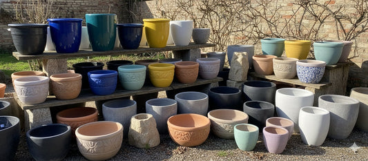 A diverse collection of ceramic planters in various styles and colors, arranged outdoors