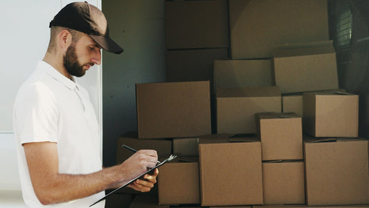 A man stands next to the truck, inspecting the delivery.