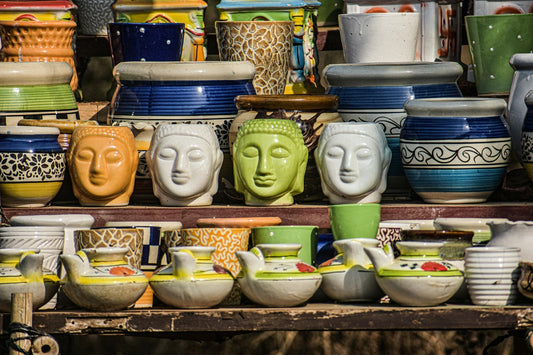 A collection of colorful pottery and ceramic items, including decorative pots, Buddha head sculptures, and teapots.