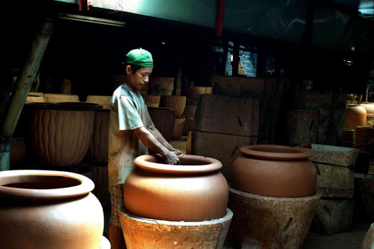 Image of a man working on a large unfired pot