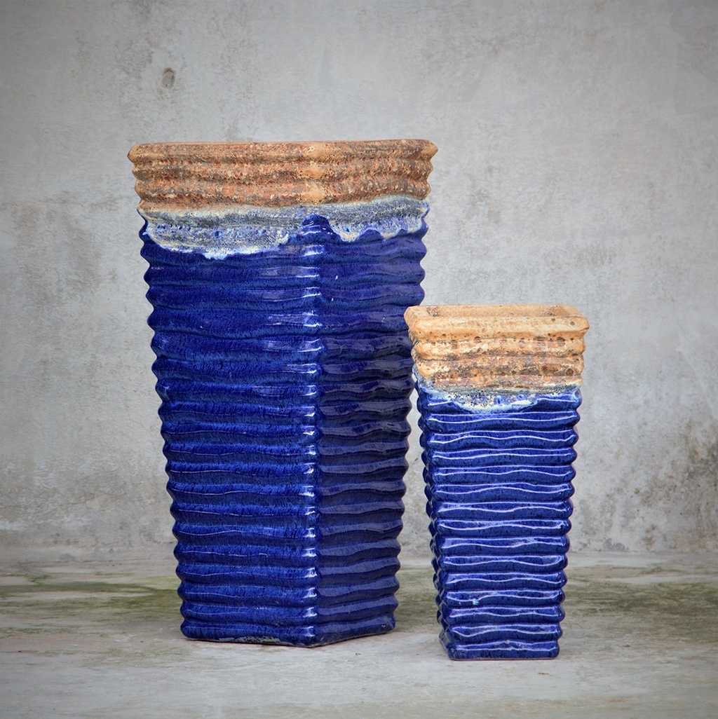 Tall, wavy ceramic planters in blue with distressed brown-orange rim