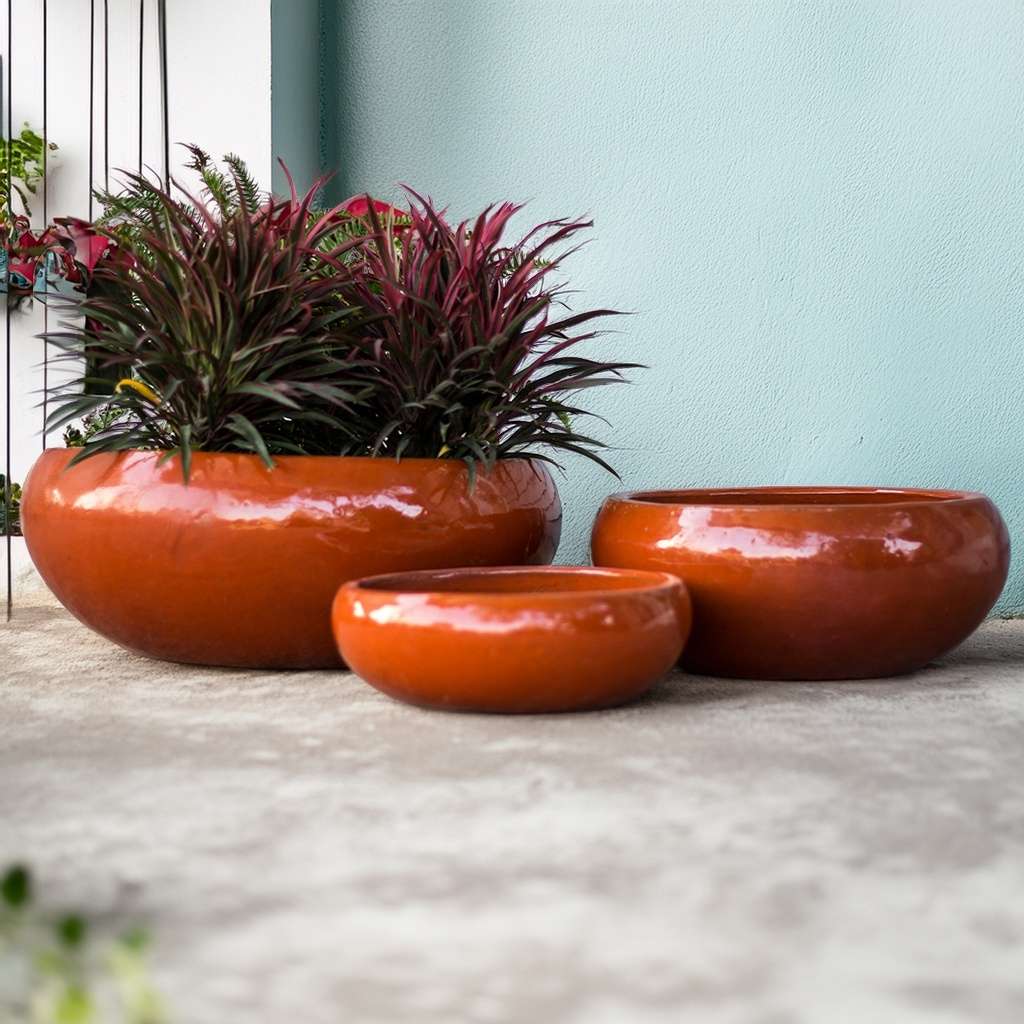 Glazed ceramic low bowl planters featuring a bright, glossy rust orange finish with a smooth, vibrant surface