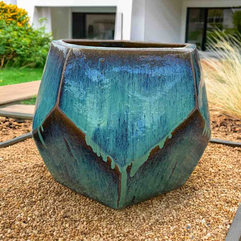 Faceted geometric polygon ceramic planter in turquoisewith brown accents, featuring sharp edges and a modern, sculptural design