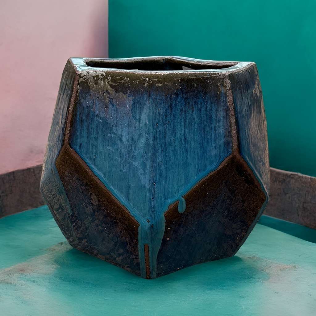 Faceted geometric polygon ceramic planter in blue with dark brown accents, featuring sharp edges and a modern, sculptural design
