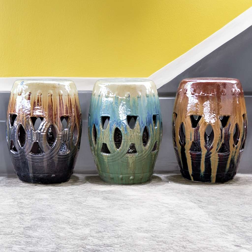 Set of ceramic garden stools in varied glazed finishes: warm browns and yellows, cool blues and greens, and rich dark browns and oranges with an intricate openwork design