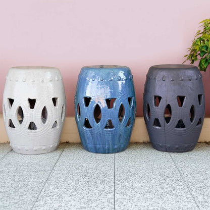 Ceramic garden stools in off-white, blue, and dark gray hues, featuring intricate openwork cutout designs for decorative outdoor seating