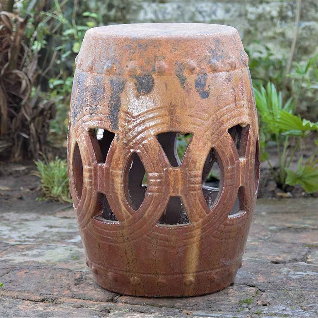 Ceramic garden stool in distressed earthy brown with decorative cut-out patterns, featuring an aged, rustic look