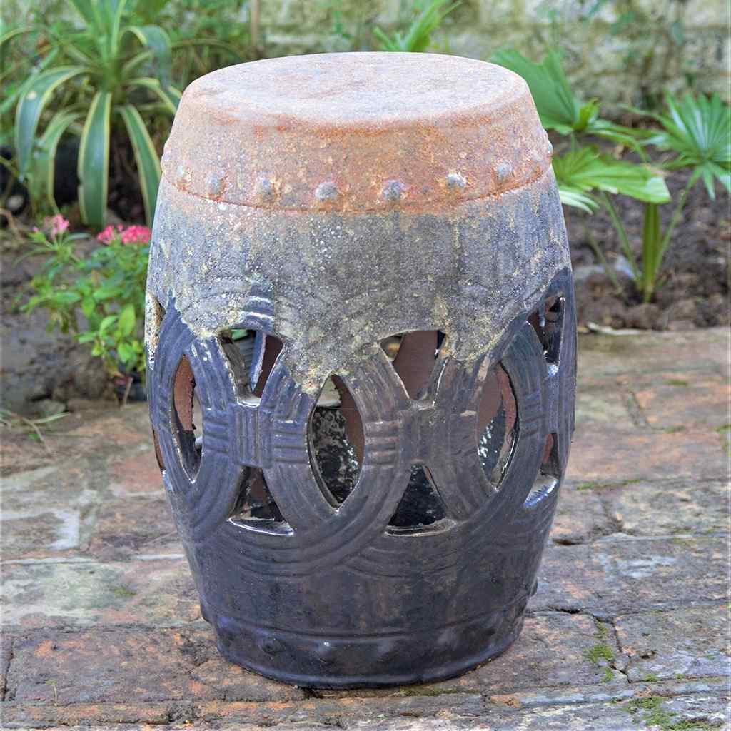 Ceramic garden stool with a gunmetal gray painted finish and a distressed, aged look, featuring a decorative lattice cut-out pattern
