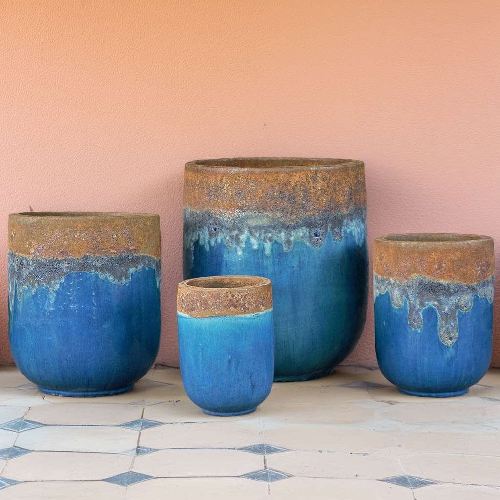 Tall glazed ceramic rounded cylinder planter in aqua blue with a contrasting unglazed rust-colored rim
