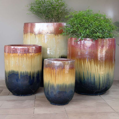 Wholesale Tall glazed ceramic rounded cylinder planters with an ombré design transitioning from deep blue at the base to vibrant yellow-gold in the middle and warm reddish-brown at the rim