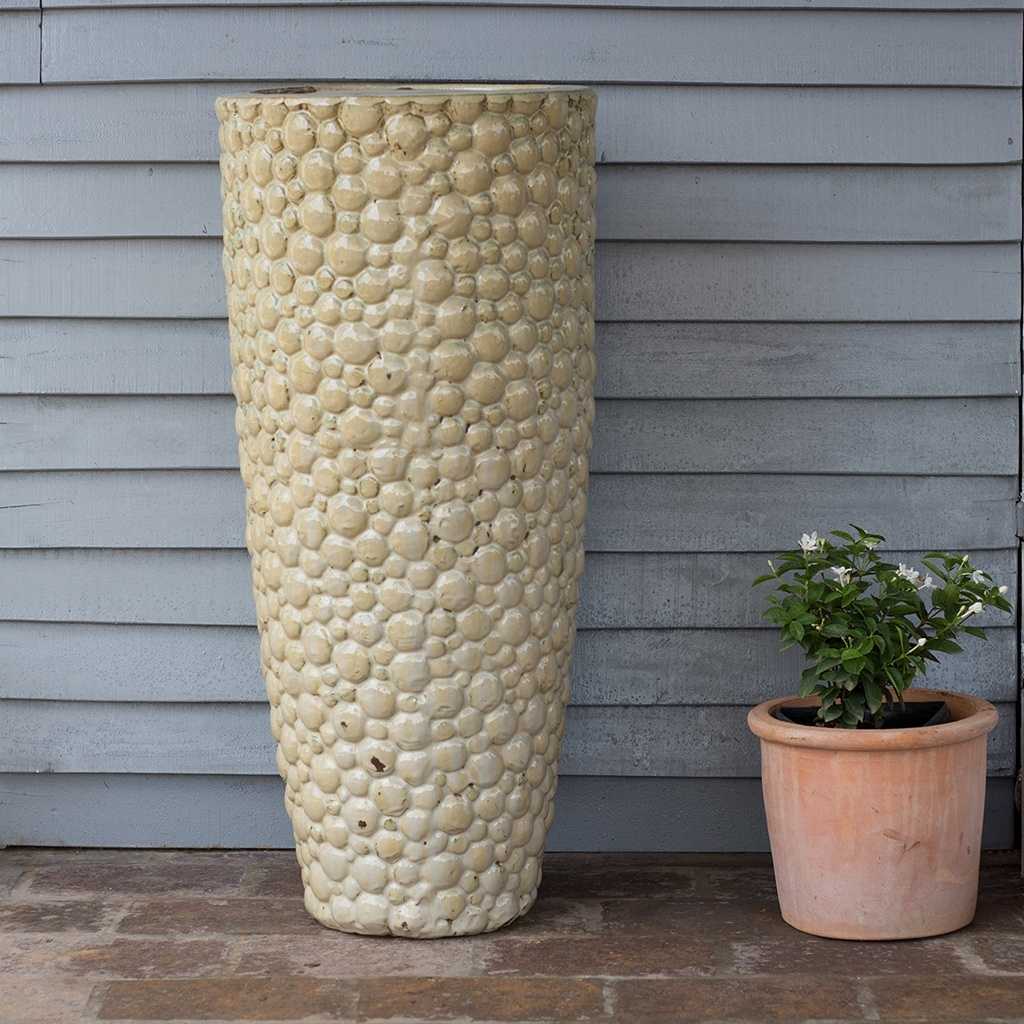 Tall ceramic planter with a pebbled texture in glossy cream