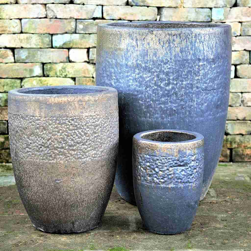 Tall rounded ceramic planters in metallic blue with a smooth, reflective finish