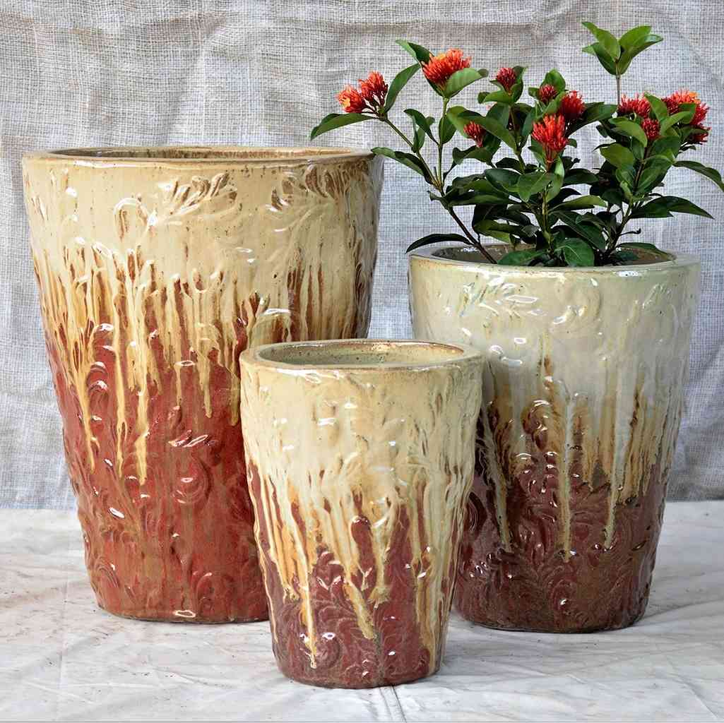 Elegant tall tapered planter in brown with a cream dripping glaze effect and an embossed foliage pattern
